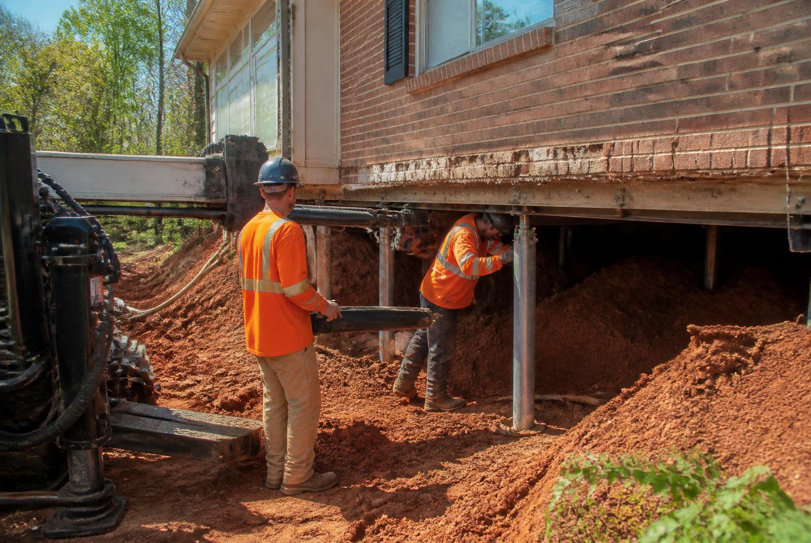 Helical pier installation under a brick ranch home
